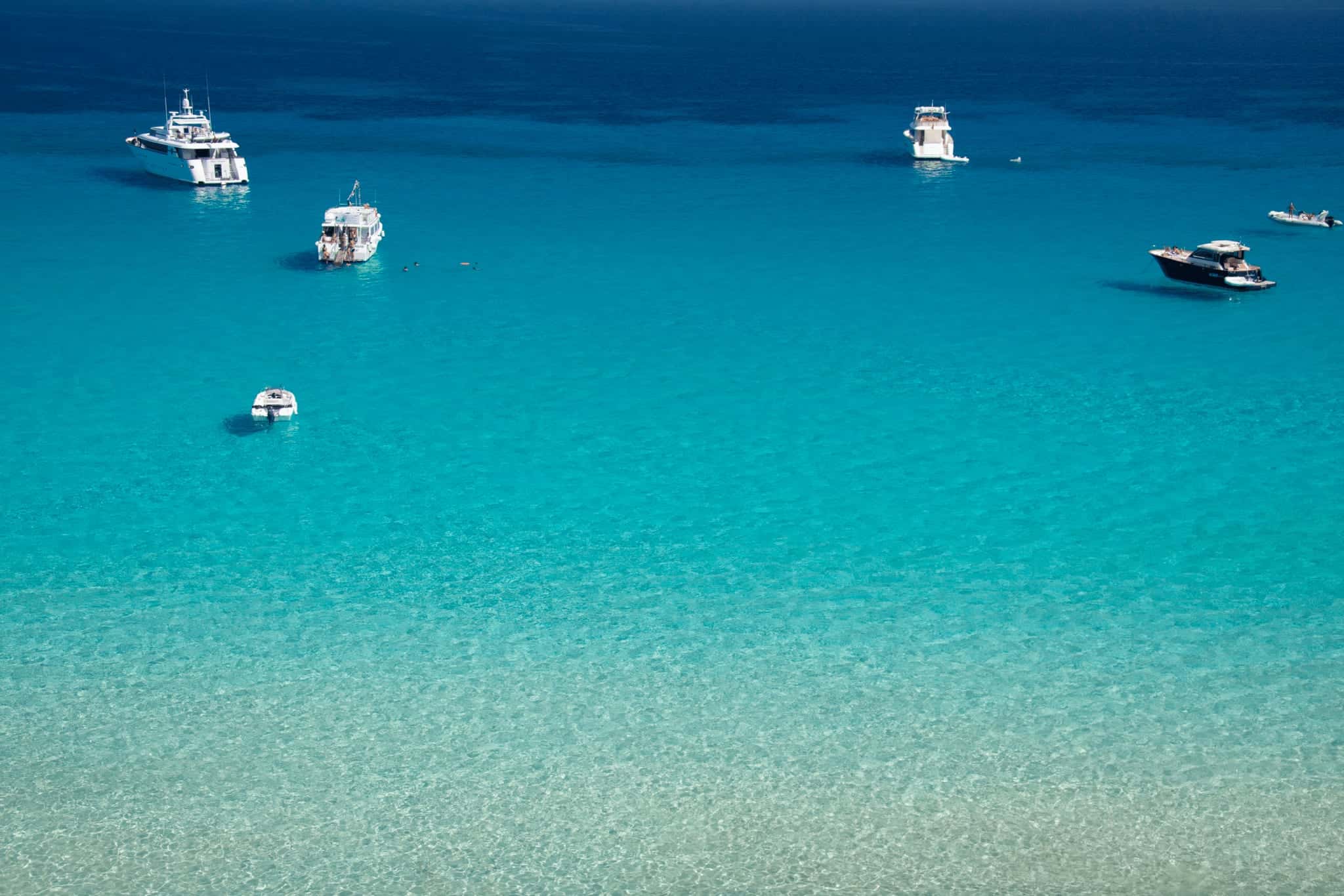Motor boats on clear turquoise water off the island of Favignana, seen from above