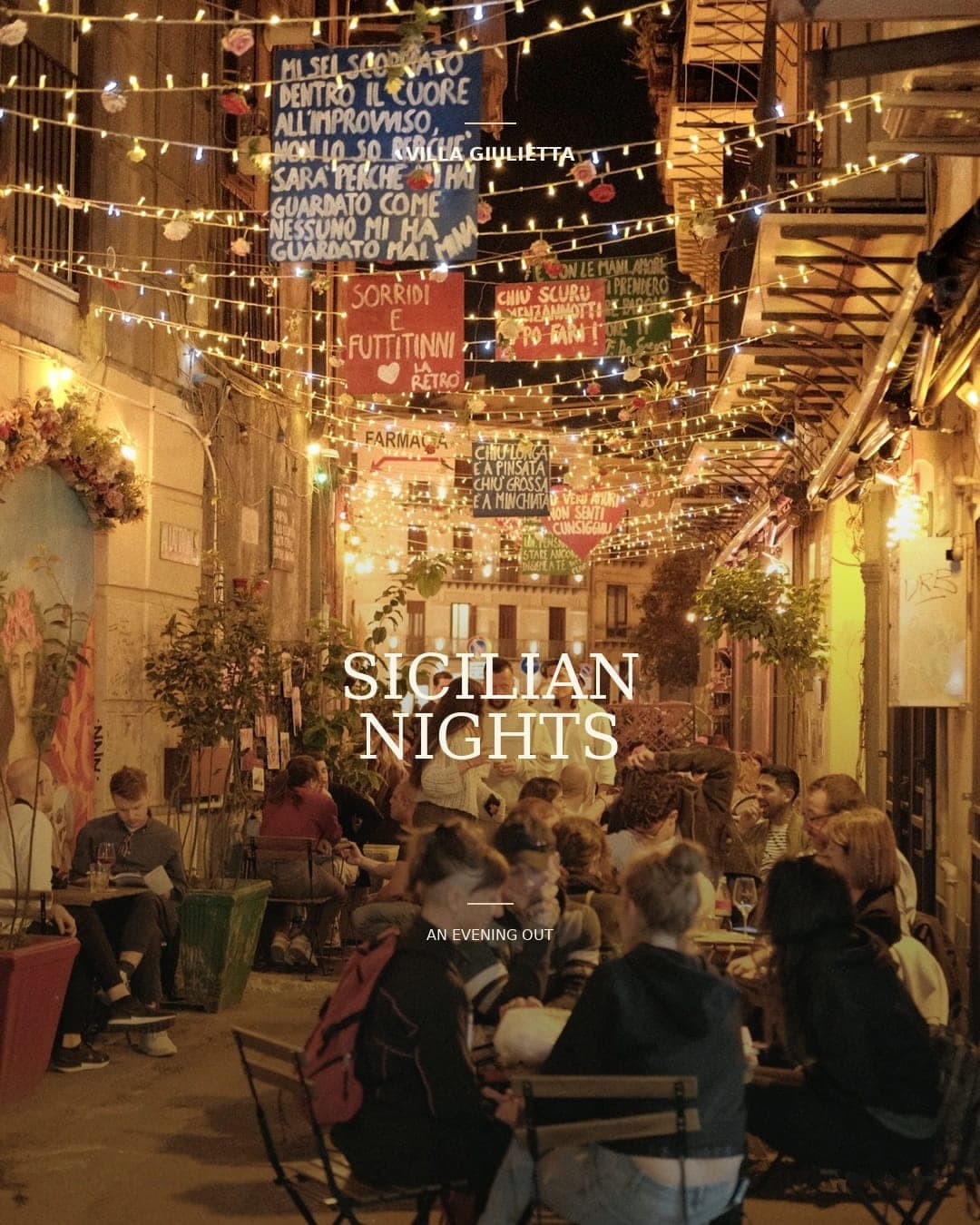 A lane at night under strings of lights and painted signs, people at tables outside, with the words “Sicilian nights, an evening out”